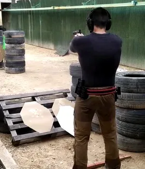 De espaldas y con cascos, apuntando a unas siluetas de cartón entre neumáticos.